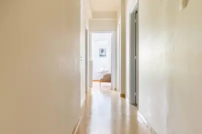 a hallway with white walls and wooden floors in a room at New Huge 5BDR/2bath Apt(+netflix)/1min toAcropolis in Athens