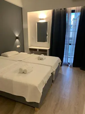 two beds in a hotel room with a television at Platon Hotel in Piraeus