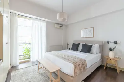 a white bedroom with a large bed and a window at Panoramic 1BR Apartment near Kallimarmaro Stadium by UPSTREET in Athens
