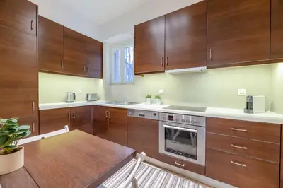 a kitchen with wooden cabinets and a wooden table at Panoramic 1BR Apartment near Kallimarmaro Stadium by UPSTREET in Athens