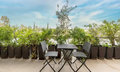 a table and four chairs on a patio with trees at Panoramic 1BR Apartment near Kallimarmaro Stadium by UPSTREET in Athens