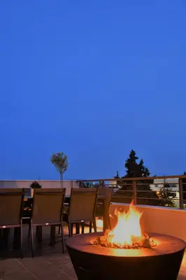 a fire pit on a patio with chairs and a blue sky at Spacious & Minimal Apartment Near Airport Peania Coniann Filoxenia in Paianía
