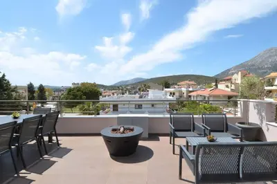 a patio with tables and chairs on a balcony with mountains at Spacious & Minimal Apartment Near Airport Peania Coniann Filoxenia in Paianía