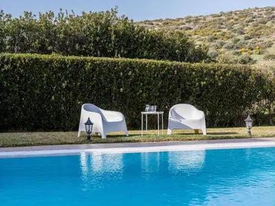 two white chairs and a table next to a pool at Phoceus Poolfront Grande Villa in Palaiá Fókaia