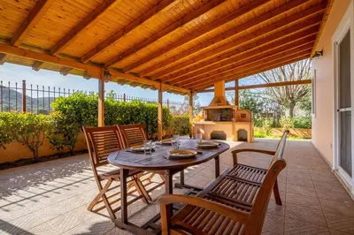 a patio with a table and chairs and a stove at Phoceus Poolfront Grande Villa in Palaiá Fókaia