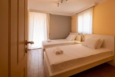 two beds in a room with a window at Phoceus Poolfront Grande Villa in Palaiá Fókaia