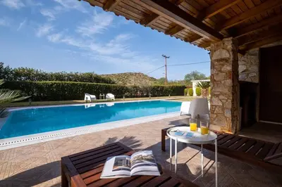 a villa with a swimming pool and a table with books at Phoceus Poolfront Grande Villa in Palaiá Fókaia