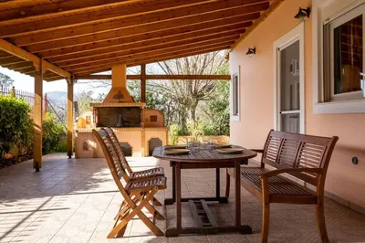 a patio with a table and two chairs and a fireplace at Phoceus Poolfront Grande Villa in Palaiá Fókaia