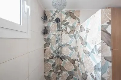 a bathroom with a shower with a floral tile wall at Athens F&K Aphrodite Apartment in Athens