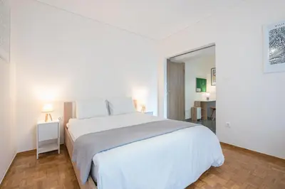 a white bedroom with a large bed and a table at Athens F&K Aphrodite Apartment in Athens