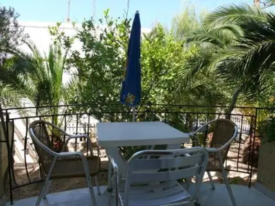 a white table and two chairs and a blue umbrella at Senia Studios in Agia Marina Aegina
