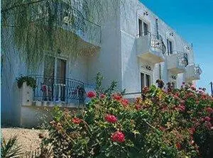 a large white building with flowers in front of it at Senia Studios in Agia Marina Aegina