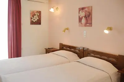 a bedroom with two beds and two pictures on the wall at Senia Studios in Agia Marina Aegina