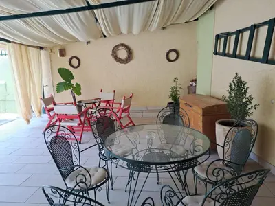 a patio with a glass table and chairs at Dimitris place near Athens airport in Koropíon