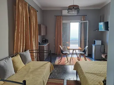 a living room with a bed and a table with chairs at Dimitris place near Athens airport in Koropíon