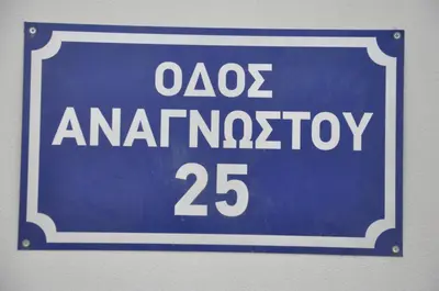 a blue sign that reads oos antarrosis at Dimitris place near Athens airport in Koropíon
