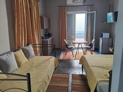 a living room with a bed and a table with chairs at Dimitris place near Athens airport in Koropíon