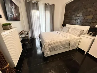 a bedroom with a white bed and a black floor at Beautiful Studio With Private Yard in Athens