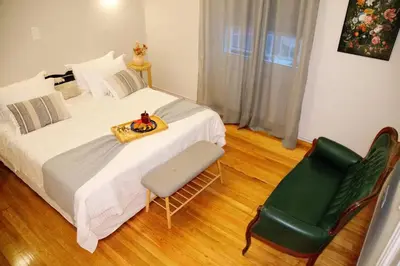 a bedroom with a bed and a green chair at Aroura Neoclassical Home 3BR 2BA in Athens
