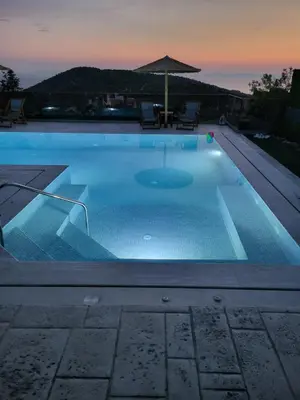 a swimming pool at night with an umbrella at Stergiou Luxury Apartments with shared pool in Anavissos