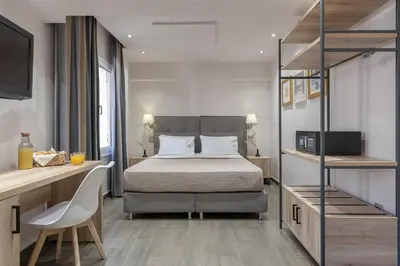 a bedroom with a bed and a desk and a television at Piraeus City Hotel in Piraeus