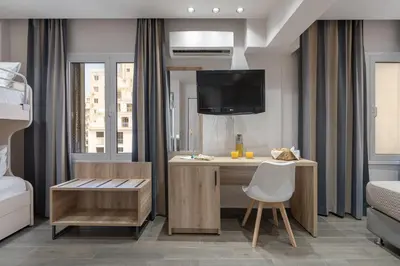 a bedroom with a desk and a tv and a bed at Piraeus City Hotel in Piraeus