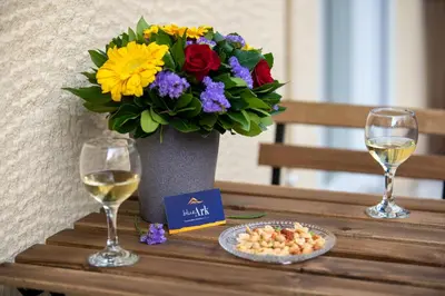 a table with two glasses of wine and a vase of flowers at Blue Ark Gate to History in Athens