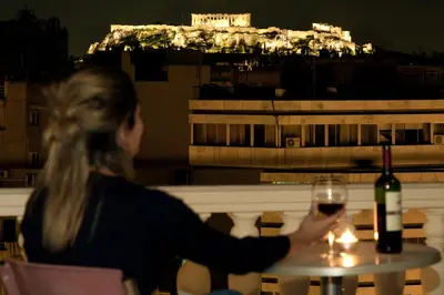 a woman sitting at a table with a glass of wine at Athens Odeon Hotel in Athens