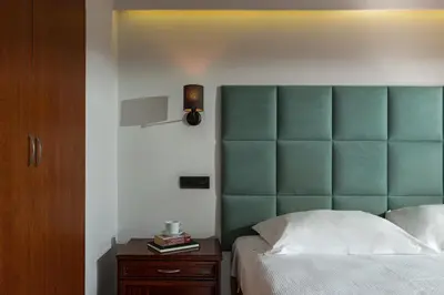 a bedroom with a green headboard and a wooden cabinet at Athens Odeon Hotel in Athens