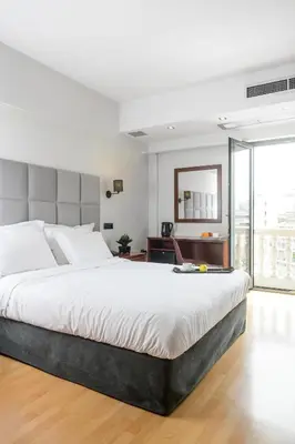a bedroom with a large bed and a large window at Athens Odeon Hotel in Athens