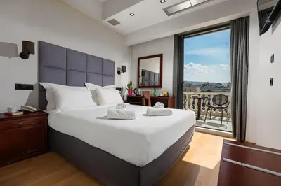 a bedroom with a large bed and a large window at Athens Odeon Hotel in Athens