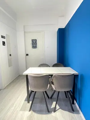 a table and chairs in a room with a blue wall at uoohome7 garden one bedroom in Athens