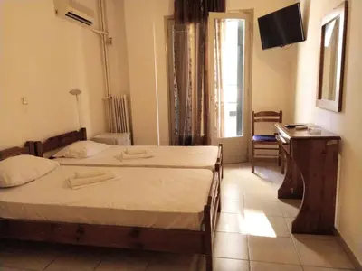 a bedroom with two beds and a desk and a television at Delfini Hotel in Piraeus