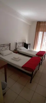 two twin beds in a room with a window at Delfini Hotel in Piraeus