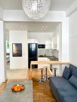 a living room with a blue couch and a kitchen at Modern 3BR Maisonette with garden 10 min from Acropolis in Athens
