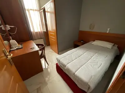 a small bedroom with a bed and a desk at Piraeus Acropole Hotel in Piraeus