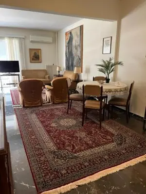 a living room with a table and chairs and a rug at Spacious and sunny appartment in Cholargos in Athens