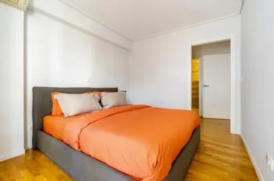 a bedroom with an orange bed in a white room at Pratinou Penthouse in Athens