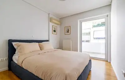 a bedroom with a large bed and a window at Pratinou Penthouse in Athens