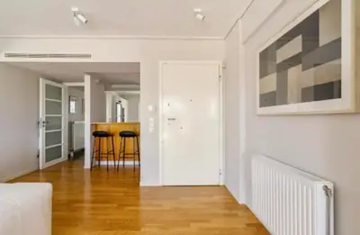 a living room with white walls and wood floors at Pratinou Penthouse in Athens