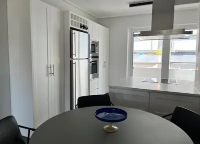 a kitchen with a table with chairs and a refrigerator at Pratinou Penthouse in Athens