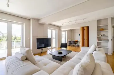 a living room with a white couch and a tv at Pratinou Penthouse in Athens