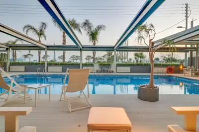 a pool with chairs and a palm tree in a building at Palace Hotel Glyfada in Athens