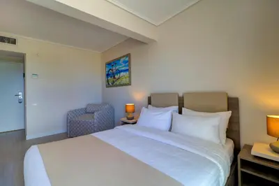 a bedroom with a large white bed and a chair at Palace Hotel Glyfada in Athens