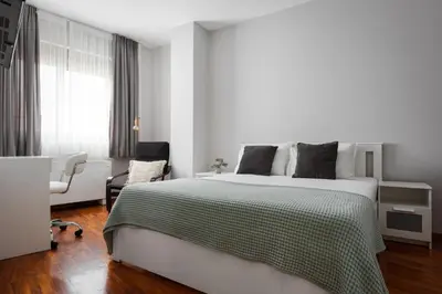 a white bedroom with a large bed and a chair at Varkiza Escape Residence in Vari