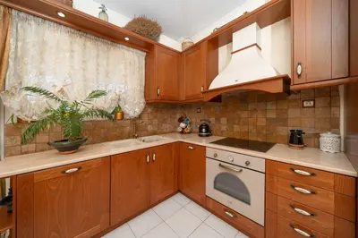 a kitchen with wooden cabinets and a sink and a window at Vintage Place Near ATH Airport in Markopoulo