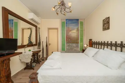 a bedroom with a white bed and a television at Vintage Place Near ATH Airport in Markopoulo