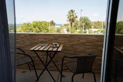 a table and chairs on a balcony with a view of the ocean at Parthenis Riviera Hotel in Athens