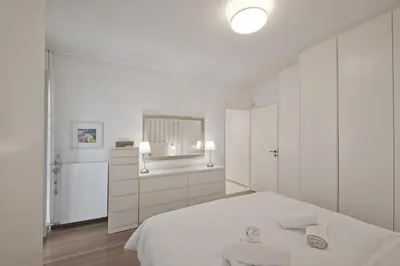 a white bedroom with a bed and a mirror at Belva Blue Glyfada Modern 2BR Walk to Ctr & Beach in Athens