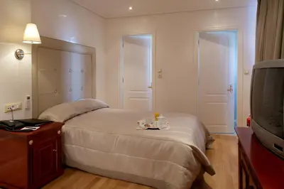 a hotel room with a bed and a tv at Piraeus Theoxenia Hotel in Piraeus